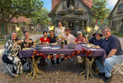 Group of people sitting at a table outside a whimsical tea shop with decorative elements.